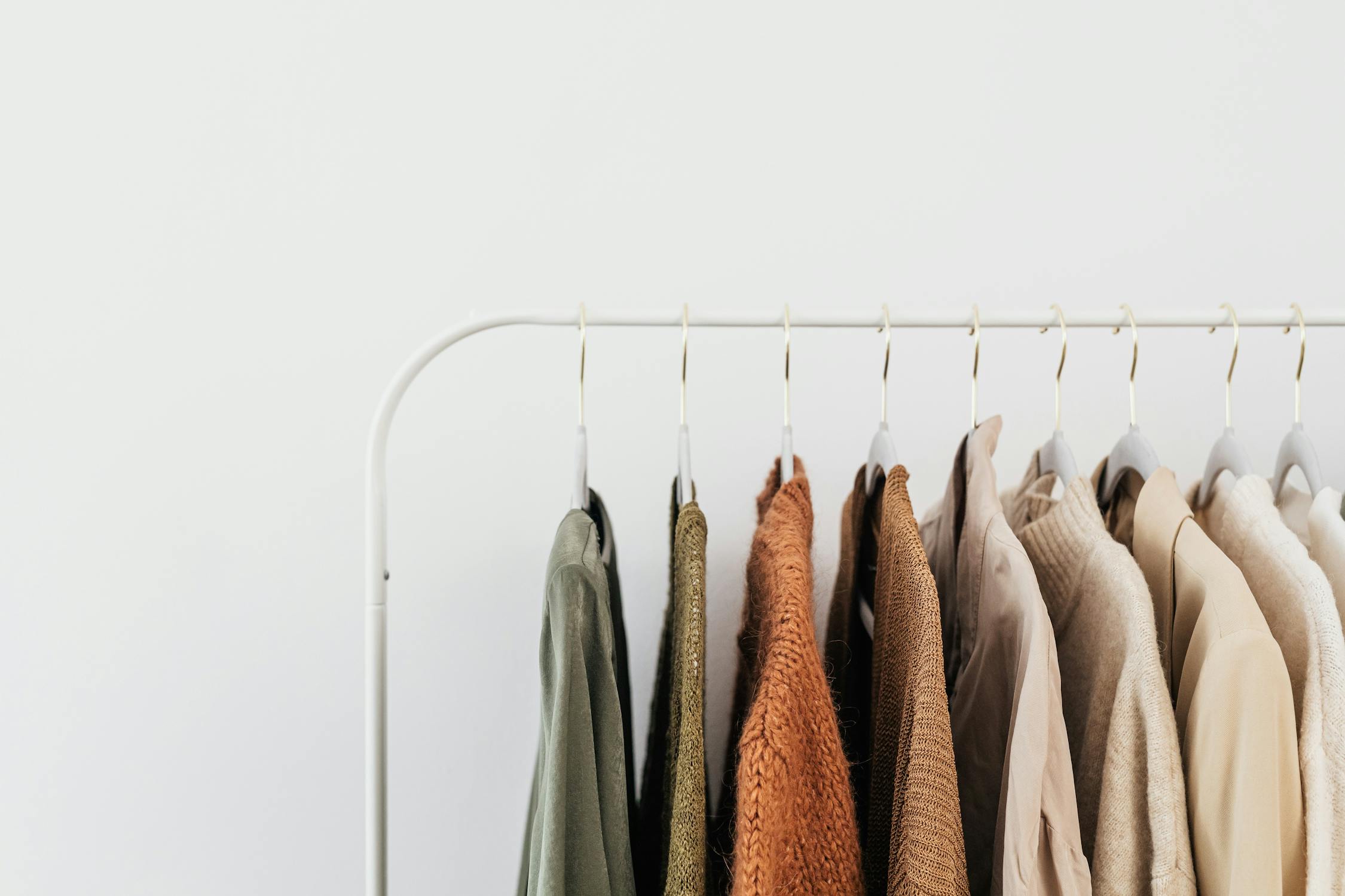 Neatly organized clothing rack displaying neutral-toned garments on hangers