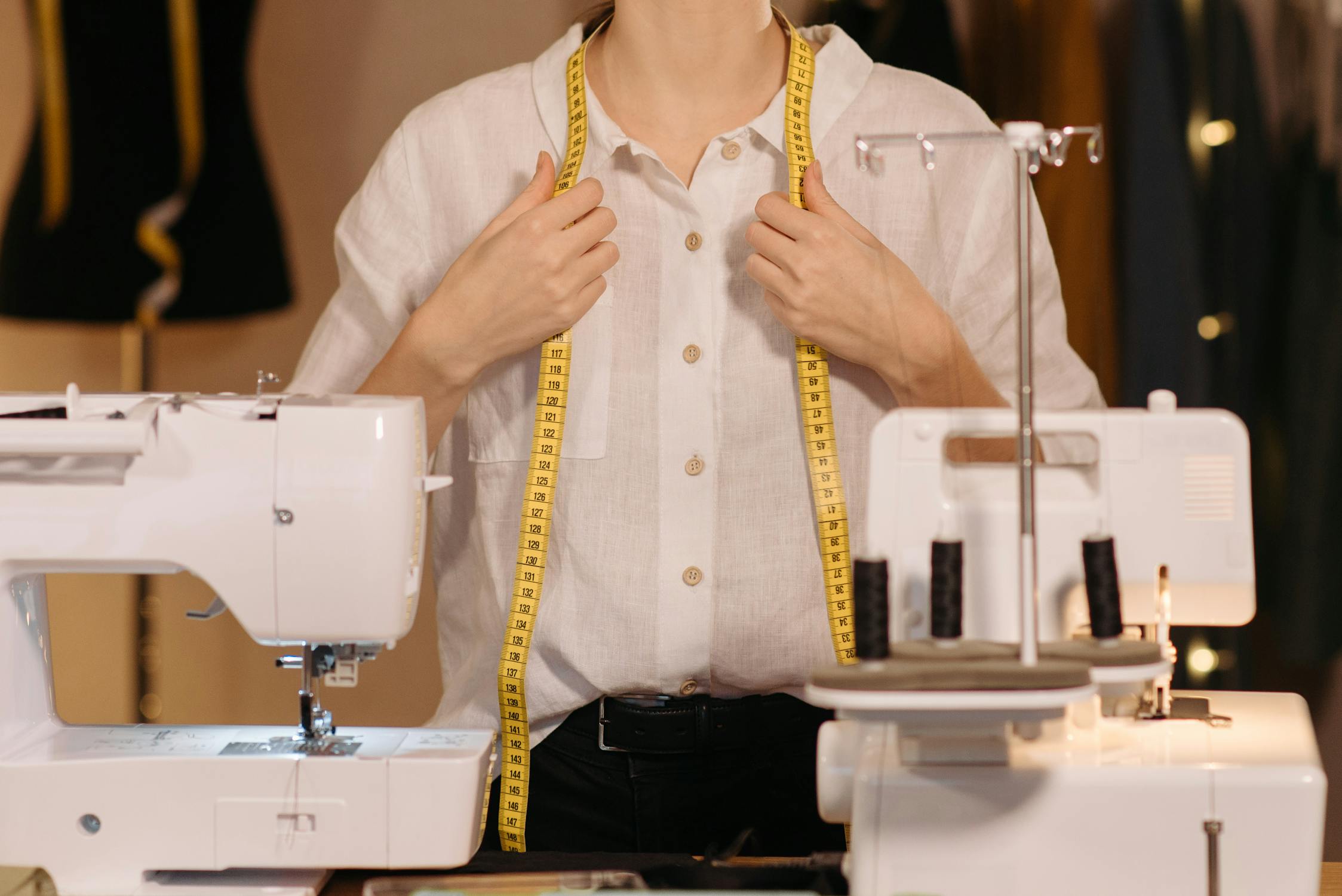 Professional tailor with measuring tape and sewing machines in a well-organized workspace